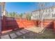This backyard features a red wooden fence, walkway stones, and mature trees at 3529 S Sherwood Se Rd, Smyrna, GA 30082