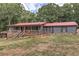 Beautiful gray house with red metal roof, front porch with wooden railings and landscaped yard surrounded by mature trees at 616 Rich Davis Rd, Hiram, GA 30141