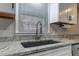 Close-up view of a modern kitchen sink with gray granite countertops and white cabinets at 616 Rich Davis Rd, Hiram, GA 30141