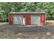 Red outbuilding with two garage doors and one entry door sits on a gravel lot at 616 Rich Davis Rd, Hiram, GA 30141