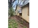 Side view of a weathered yellow house, showing boarded windows and untamed vegetation at 1771 Hosea L Williams Se Dr, Atlanta, GA 30317
