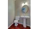 Stylish half-bath with pedestal sink, wood floors, and decorative mirror and lighting at 922 Gardenia Curv, Canton, GA 30114