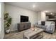Comfortable living room features wood floors, a TV console and an adjacent kitchen area at 11930 Guelph Cir, Hampton, GA 30228