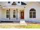 Charming white brick home featuring a decorative wood front door, complemented by arched windows and black accent pillars at 384 Minix Rd, Sharpsburg, GA 30277