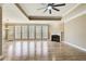 Spacious living room with hardwood floors, fireplace, ceiling fan, and large windows overlooking the backyard at 384 Minix Rd, Sharpsburg, GA 30277