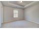 Bright bedroom featuring neutral walls, plush carpeting, tray ceiling, and natural light from a window at 124 Felicity Pike, Locust Grove, GA 30248