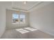 Bedroom featuring carpet floors, a tray ceiling, and a sunlit window at 124 Felicity Pike, Locust Grove, GA 30248