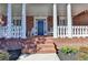 Inviting front porch with classic columns, rocking chairs, and a stylish blue front door at 253 Hailwood Ct, Suwanee, GA 30024