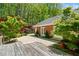 Spacious patio with double doors and manicured landscaping, adjacent to a wooden deck at 1790 Mountain Farm Rd, Woodstock, GA 30188