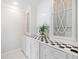 White cabinetry with a decorative glass door cabinet and a black and white checkerboard countertop with a green potted plant at 1790 Mountain Farm Rd, Woodstock, GA 30188