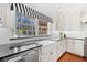 Bright kitchen with white cabinetry, farmhouse sink, stainless appliances, and black and white striped awning at 1790 Mountain Farm Rd, Woodstock, GA 30188