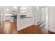 Open concept kitchen with eat-in island, white cabinetry, black countertops and hardwood floors leading into a hallway at 1790 Mountain Farm Rd, Woodstock, GA 30188