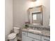 Cozy powder room featuring white cabinetry, granite countertop and a decorative mirror with brushed nickel hardware at 105 Ivey Way, Woodstock, GA 30188