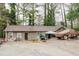 Side angle view of a single story tan home, featuring a vehicle covered in a tarp and deciduous trees around it at 5461 Chuzzlewit Sw Ct, Lilburn, GA 30047