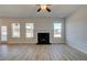 Spacious living room showcasing wood-look floors, a fireplace, large windows, and a ceiling fan at 128 Dalston Cv, Stockbridge, GA 30281