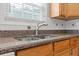 Granite countertop with a stainless steel sink and wooden cabinets, creating a functional and stylish kitchen space at 709 Mohansic Ave, Loganville, GA 30052