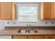 Bright kitchen with granite countertops, stainless steel sink and warm wood cabinets under a window at 709 Mohansic Ave, Loganville, GA 30052