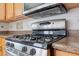 Close-up showcasing a stainless steel gas range with overhead microwave and detailed tile backsplash in a well-equipped kitchen at 709 Mohansic Ave, Loganville, GA 30052