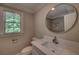 Bathroom featuring quartz countertop, round mirror, neutral paint and view of tiled shower at 1261 William Robert Sw Dr, Marietta, GA 30008