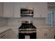 Close-up of kitchen features stainless steel stove and microwave, white cabinetry, and tile backsplash at 1261 William Robert Sw Dr, Marietta, GA 30008