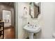 Elegant powder room featuring a pedestal sink, decorative mirror, and stylish fixtures at 560 Collier Nw Rd, Atlanta, GA 30318