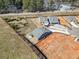 An aerial shot of a single-story home with adjacent undeveloped land near a road and commercial businesses at 144 Laurel Farms Ln, Dallas, GA 30157