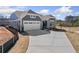 A view of the home showcasing the long driveway, two-car garage, and landscaping, on a partially sunny day at 144 Laurel Farms Ln, Dallas, GA 30157