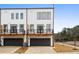 Modern townhome showing white siding, black trim, personal garages, and charming balconies under a bright blue sky at 1084 Brookglynn Trce, Decatur, GA 30032