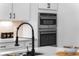Close-up of stainless steel double ovens in a modern kitchen with sleek black hardware at 1084 Brookglynn Trce, Decatur, GA 30032