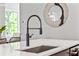 Close up of kitchen island with quartz counters, stainless sink, black faucet, and decorative mirror at 2150 Tidwell Ln # 5, Atlanta, GA 30318