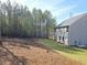 Backyard view showcasing a well-maintained lawn, mature trees, and a newly constructed home at 75 Heyman Dr, Covington, GA 30016