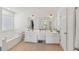 Inviting bathroom featuring a tub, double sinks, a vanity, a large mirror, and contemporary lighting fixtures at 807 Plaintain Dr, Woodstock, GA 30188