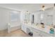 Light-filled bathroom with a window-side tub, double sinks, a vanity, a large mirror, and modern fixtures at 807 Plaintain Dr, Woodstock, GA 30188