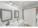 Well-lit bathroom features a double vanity with sleek fixtures, a framed mirror, and a shower with a white curtain at 807 Plaintain Dr, Woodstock, GA 30188