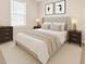 A well-lit bedroom with a tufted headboard, neutral-colored walls, and tasteful decor at 6420 Magnolia Way, Morrow, GA 30260