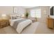 A bright bedroom features neutral carpeting, window, and is furnished with lamps, bed, dresser, and chair at 6420 Magnolia Way, Morrow, GA 30260