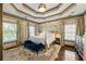 Spacious main bedroom showcasing a tray ceiling, four-poster bed, and hardwood flooring at 225 Arbor Creek Way, Roswell, GA 30076