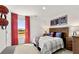 Well-lit bedroom with wooden bed frame, sporty decor, and a window with red curtains overlooking a beautiful landscape at 8588 Secretariat Dr, Lithonia, GA 30058