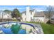 Back of house overlooking the gorgeous in-ground pool with a stone surround, grass, and fencing at 5300 Willow Park Blvd, Atlanta, GA 30349