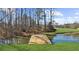 Wooden dock on a serene pond, framed by a lush green lawn and mature trees at 1511 Broadnax Mill Road, Loganville, GA 30052