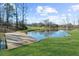 Charming pond featuring a wooden dock, surrounded by a vibrant green lawn at 1511 Broadnax Mill Road, Loganville, GA 30052