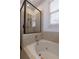 Bathroom featuring a black framed shower and white bathtub, tiled walls, and a window providing natural light at 301 Fortune St, Atlanta, GA 30312