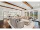 Open floor plan living room with exposed wood beams, hardwood flooring, and neutral colored furniture at 1005 W Kingston Dr, Atlanta, GA 30342