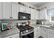 Well-lit kitchen offers sleek stainless steel appliances, granite countertops, and stylish gray backsplash at 1914 Lakeshore Overlook Nw Cir, Kennesaw, GA 30152