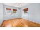 Bedroom featuring gleaming hardwood floors, three sunlit windows, and a ceiling fan at 1485 Camelot Ln, Tucker, GA 30084