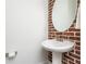 Chic powder room featuring a pedestal sink, decorative mirror, and brick accent wall at 1199 Huff Nw Rd # 109, Atlanta, GA 30318