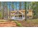 Attractive two-story home with a covered front porch, stone accents, and a serene wooded backdrop at 8640 Embrey Dr, Jonesboro, GA 30236