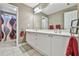 Well-lit bathroom with a double sink vanity, decorative mirror, and shower with patterned curtain at 2837 Captain Ct, Dacula, GA 30019