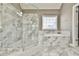 Elegant bathroom featuring a glass enclosed shower and separate soaking tub with marble tile surround at 2837 Captain Ct, Dacula, GA 30019