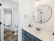 Stylish bathroom with a round mirror, blue vanity, and elegant herringbone-patterned floors at 5170 Deerlake Dr, Alpharetta, GA 30005